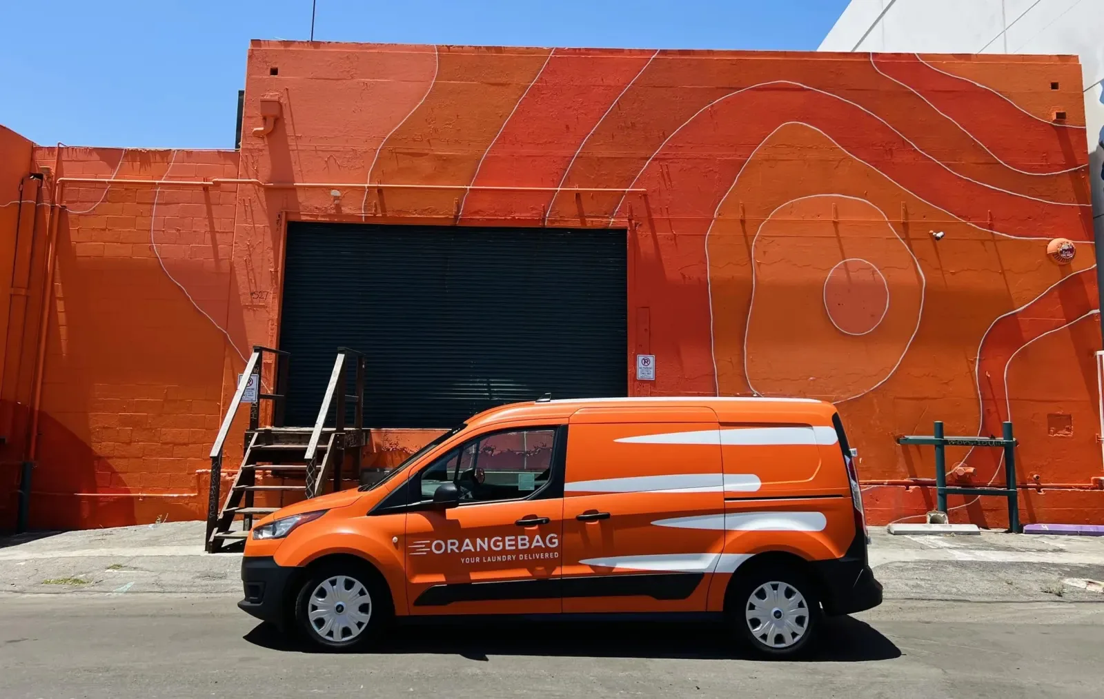 An OrangeBag delivery van parked in front of the painted orange wall at the Los Angeles plant