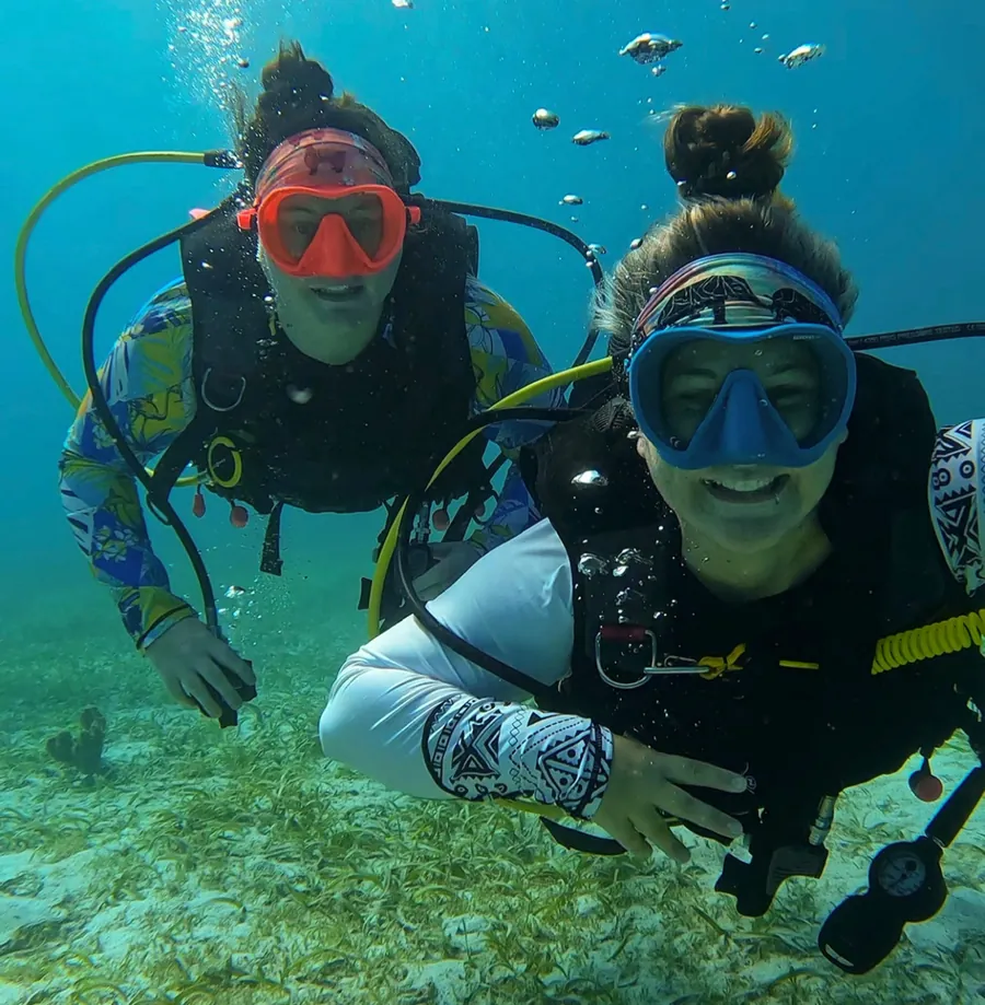 Mariya and Sam scuba diving over sea grass