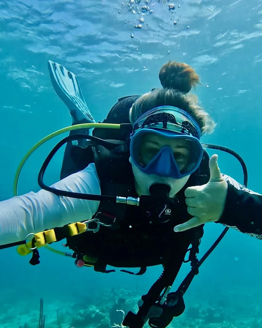 Mariya giving a shaka sign underwater in a blue mask