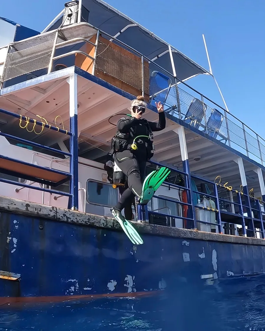 A diver in green fins stepping off the dive boat